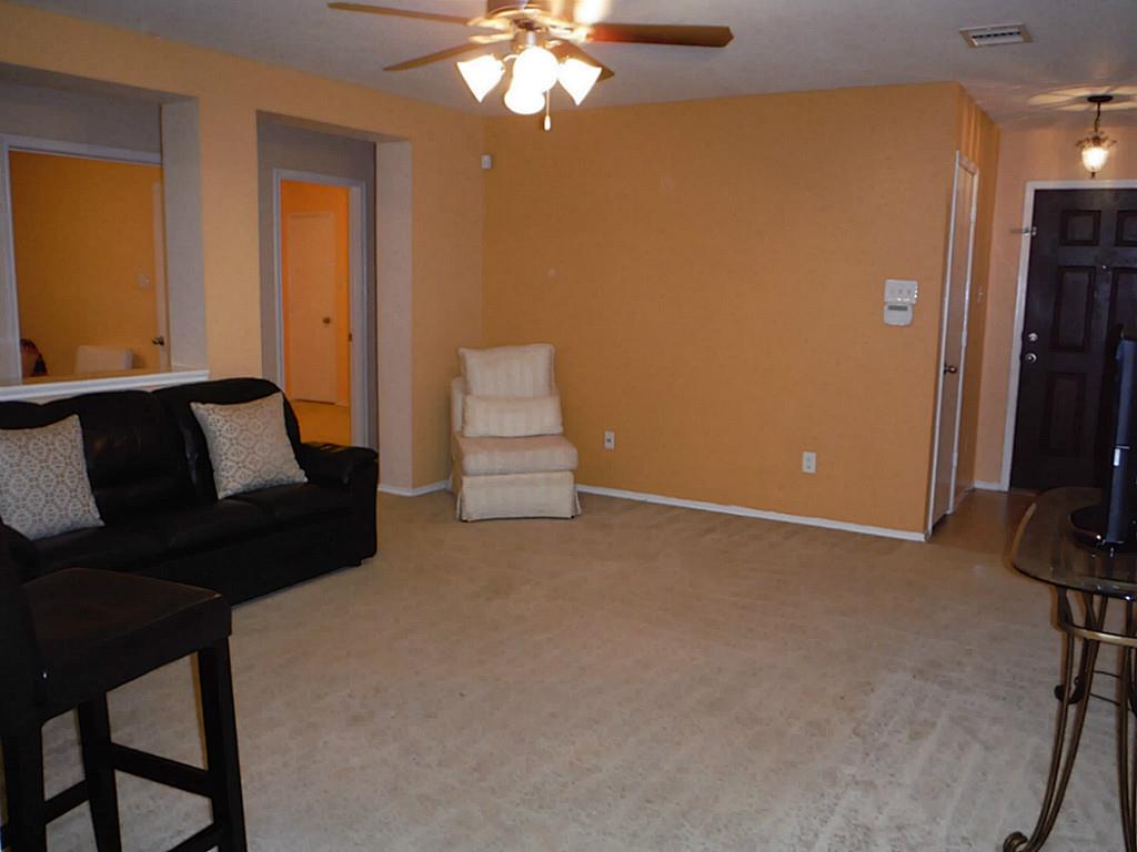 3142 Aspen Fair Trail Spring, TX 77389 - Photo 8 of 22 Spacious living room with warm, beige walls and soft carpet. Features a ceiling fan, and an open doorway design, creating a cozy and inviting atmosphere.