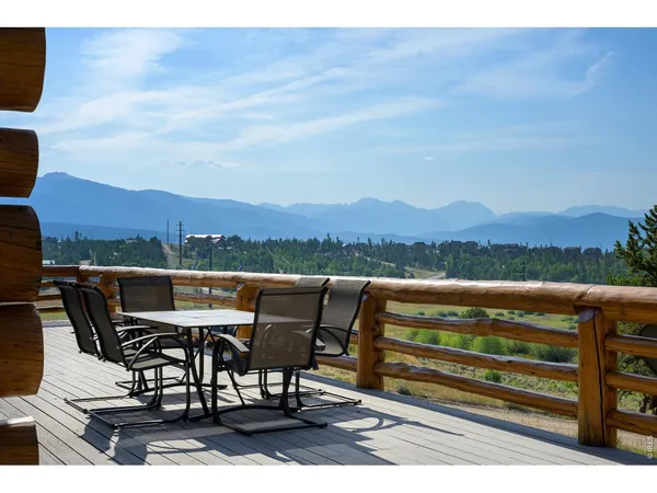 a roof deck with table and chairs and potted plants