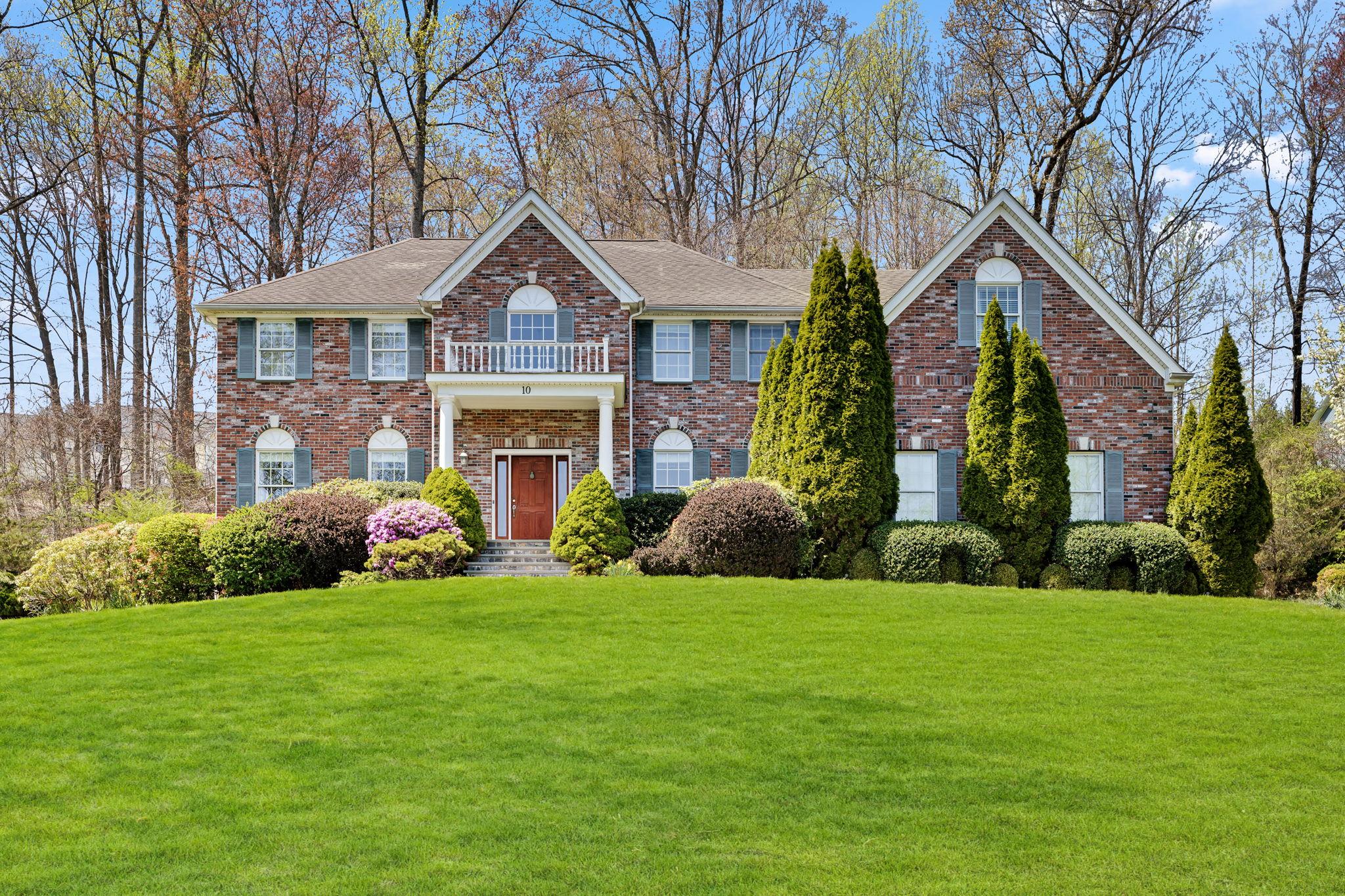 a front view of a house with garden and trees