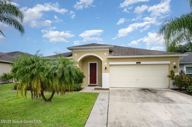 a view of a house with a yard and palm trees