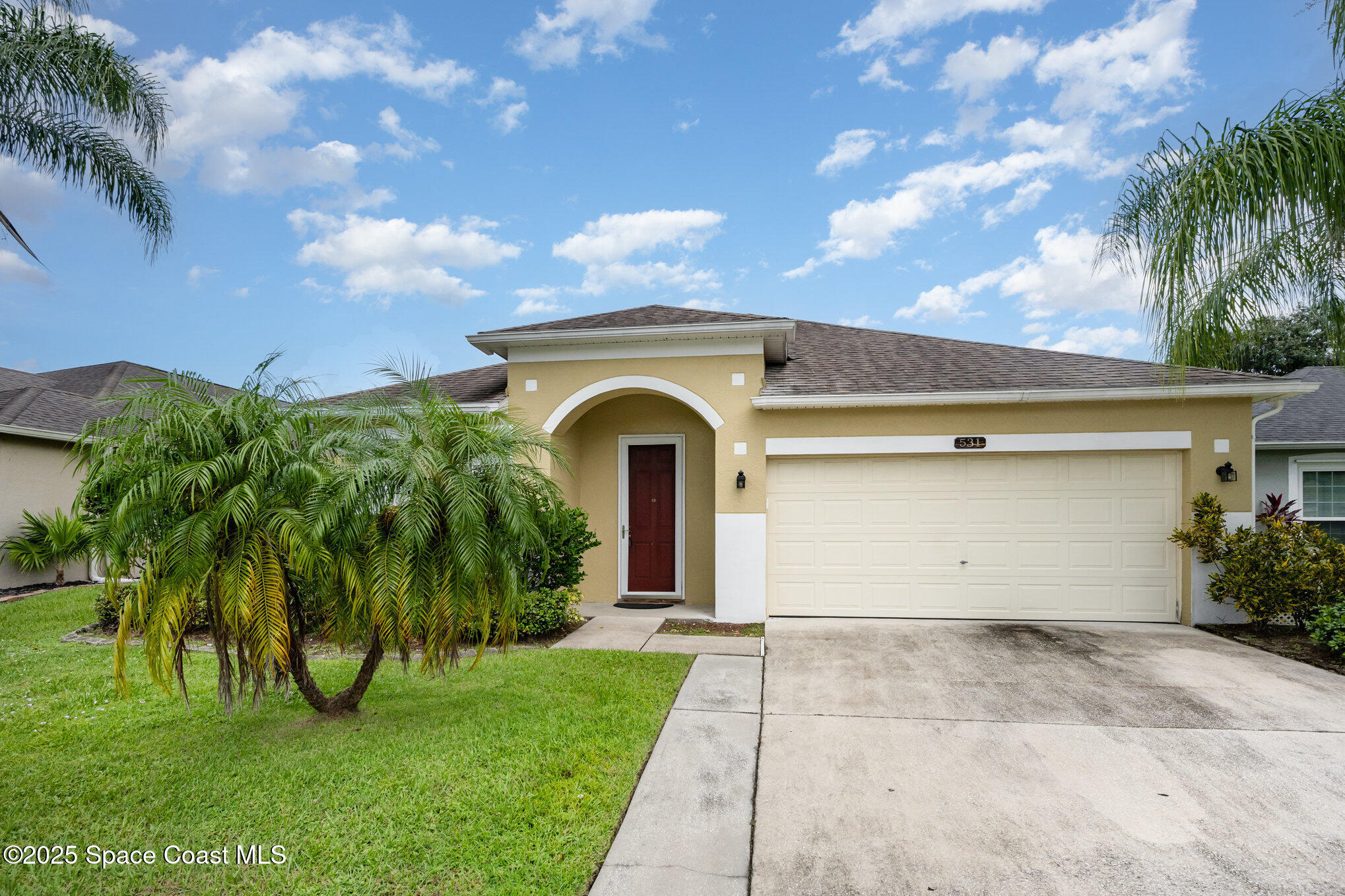 a view of a house with a yard and palm trees