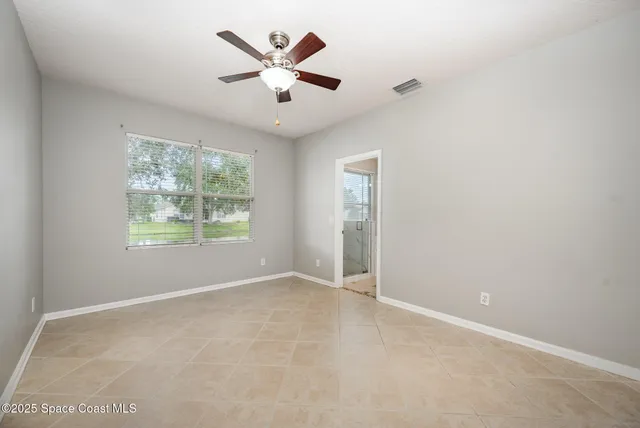 an empty room with windows and ceiling fan