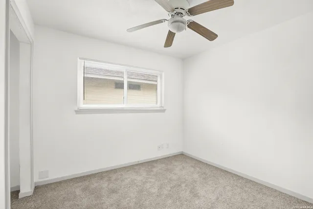 an empty room with a window and a fan