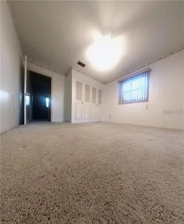 an empty room with windows and chandelier fan