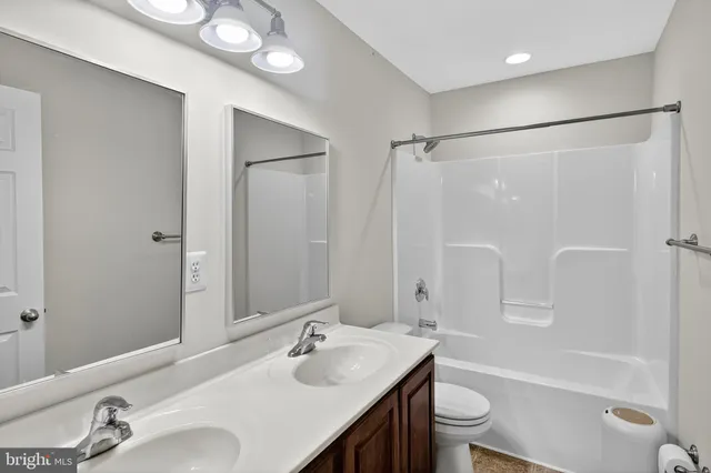 a bathroom with a double vanity sink toilet mirror and shower