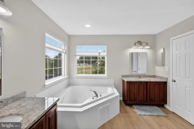 a bathroom with a granite countertop tub sink and mirror