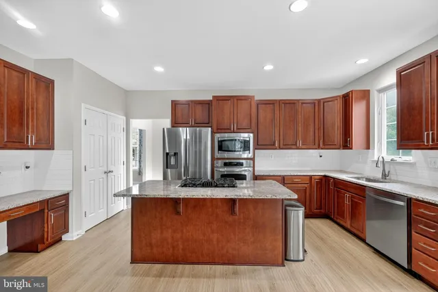 a large kitchen with stainless steel appliances wooden cabinets a sink and a stove