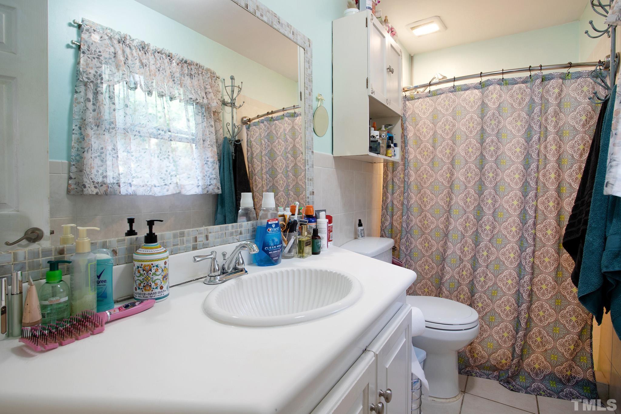 4719 Forestdale Road Raleigh, NC 27603 - Photo 24 of 28 a bathroom with a sink a toilet and a mirror