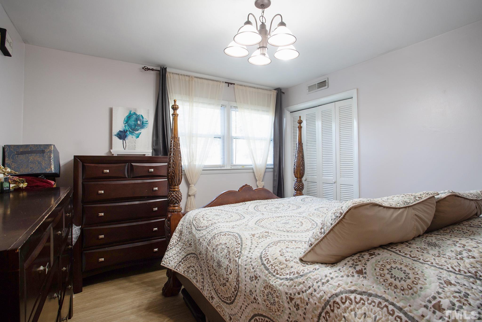 4719 Forestdale Road Raleigh, NC 27603 - Photo 27 of 28 a bedroom with a bed and a chandelier