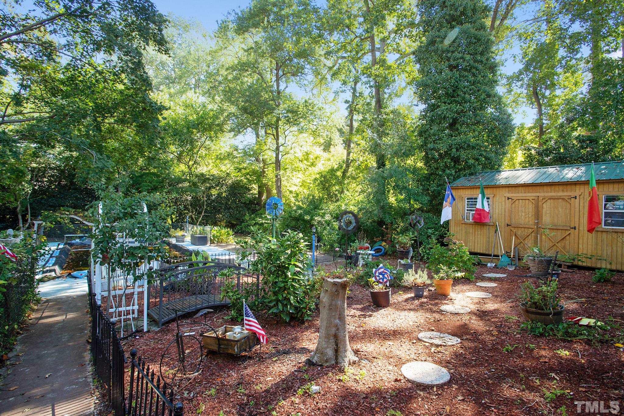 4719 Forestdale Road Raleigh, NC 27603 - Photo 4 of 28 a backyard of a house with table and chairs a barbeque with potted plants and large trees