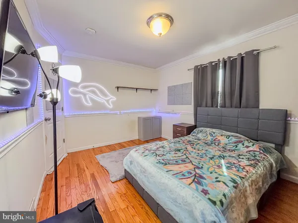 a bedroom with a bed and dresser with wooden floor
