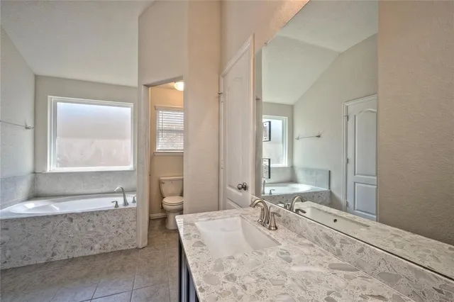 a spacious bathroom with a tub sink and mirror