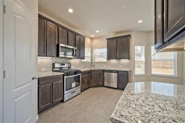 a kitchen with stainless steel appliances granite countertop a stove sink and cabinets