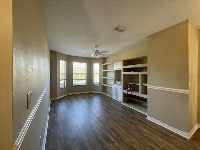 a view of an empty room with a window and wooden floor