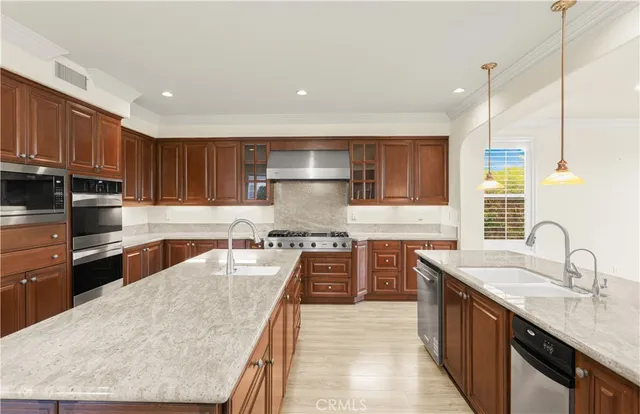 a kitchen with stainless steel appliances granite countertop wooden cabinets a sink dishwasher a stove and a refrigerator