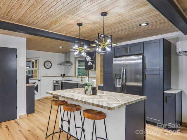 a kitchen with stainless steel appliances kitchen island granite countertop a table chairs and a chandelier