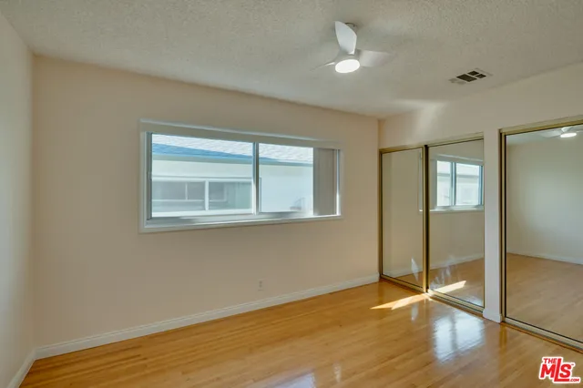 a view of empty room with wooden floor and fan