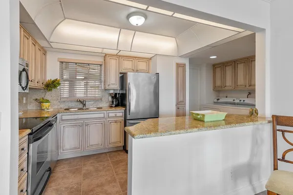 a kitchen with stainless steel appliances kitchen island granite countertop a refrigerator a stove and a sink with cabinets