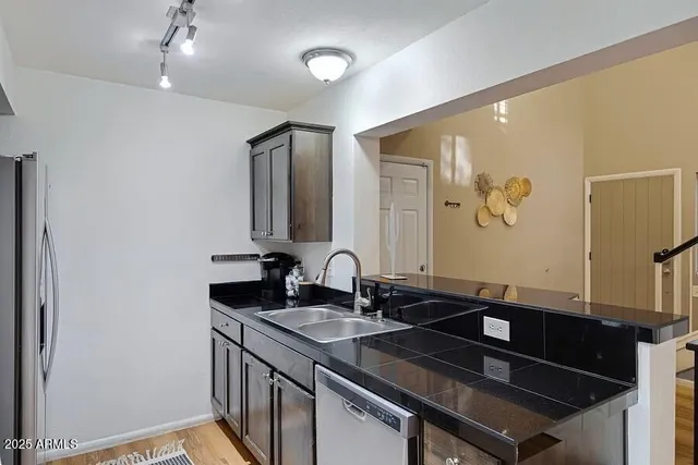 a kitchen with kitchen island granite countertop a sink stainless steel appliances and cabinets