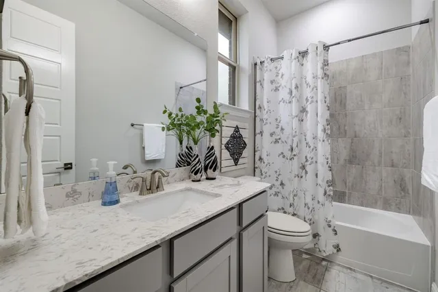 a bathroom with a granite countertop sink a toilet and shower