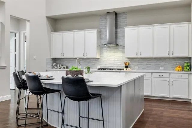 a kitchen with stainless steel appliances kitchen island granite countertop a table chairs in it and white cabinets