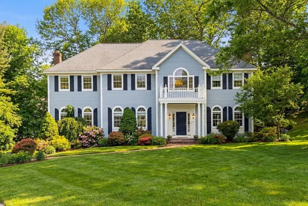 a front view of a house with a yard and trees