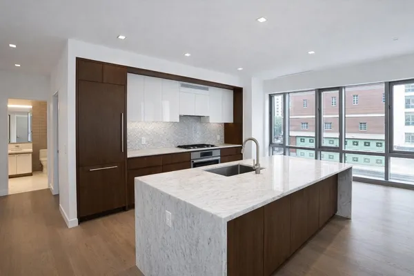 a living room with stainless steel appliances kitchen island granite countertop a refrigerator a sink and a stove with wooden floor