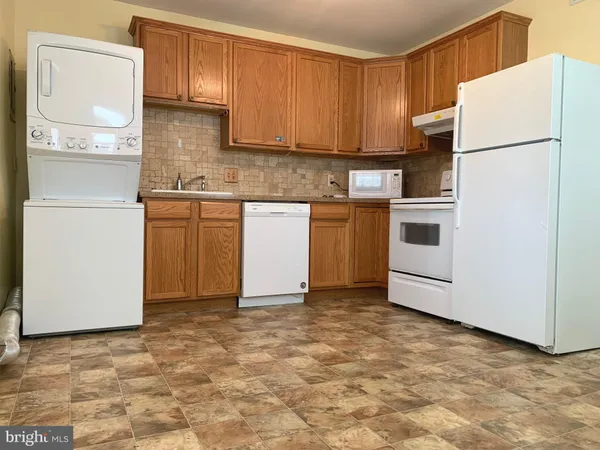 a kitchen with granite countertop a refrigerator a stove a sink and white cabinets