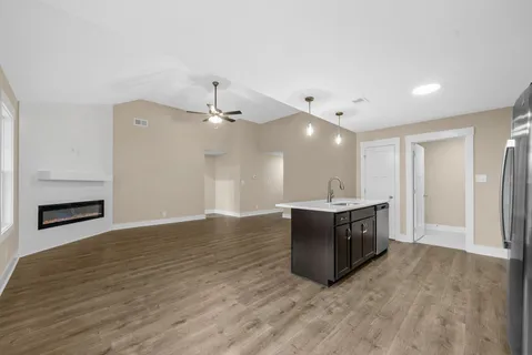 a living room with stainless steel appliances kitchen island a faucet wooden floor and a fireplace