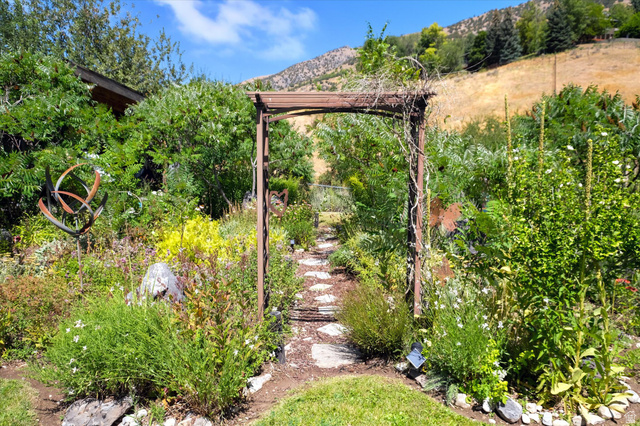 510 Spring Creek Road Providence, UT 84332 - Photo 56 of 97 Garden pathway featuring a wooden arbor, stone stepping stones, and diverse plantings