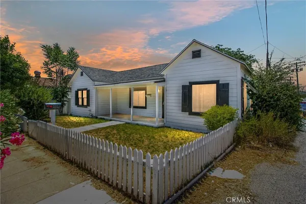 a view of a house with wooden fence next to a yard