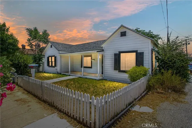 a view of a house with wooden fence next to a yard