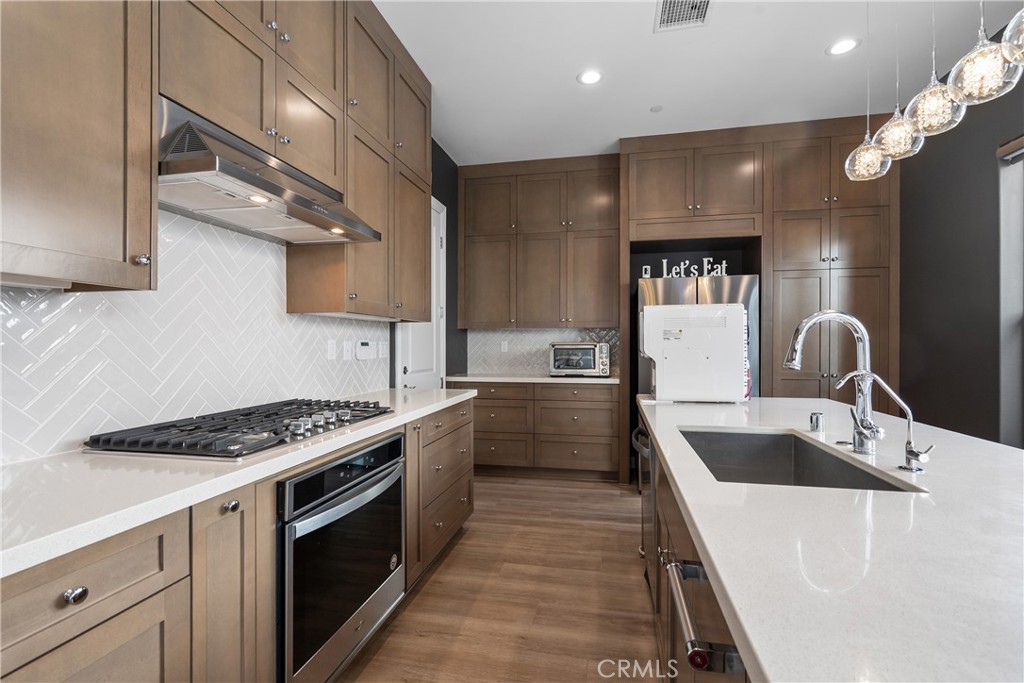 20809 Acorn Circle Porter Ranch, CA 91326 - Photo 5 of 57 a kitchen with stainless steel appliances a sink dishwasher and a stove with wooden floor