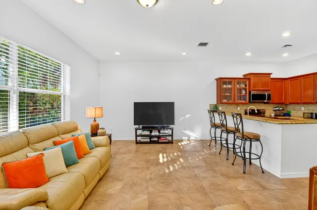 a kitchen with stainless steel appliances granite countertop a sink a stove and a dining table with white cabinets