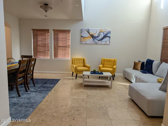 a view of a grey house with large windows and a tree