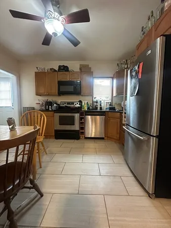 a kitchen with stainless steel appliances granite countertop a stove top oven a refrigerator a dining table and chairs with wooden floor