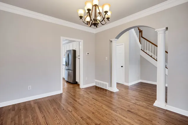 a view of a hallway with wooden floor and chandelier