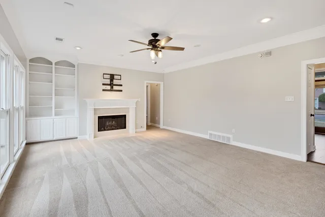 an empty room with windows and fireplace
