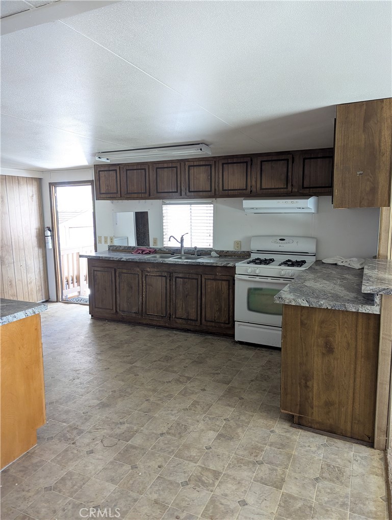 10200 Johnson Road, Unit 36 Phelan, CA 92371 - Photo 9 of 22 a kitchen with stainless steel appliances granite countertop a stove a sink and a refrigerator