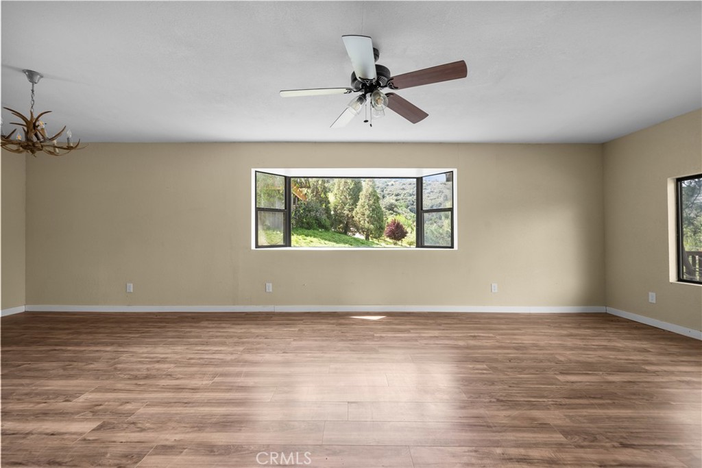 29570 Butterfield Way Tehachapi, CA 93561 - Photo 13 of 50 an empty room with wooden floor fan and windows