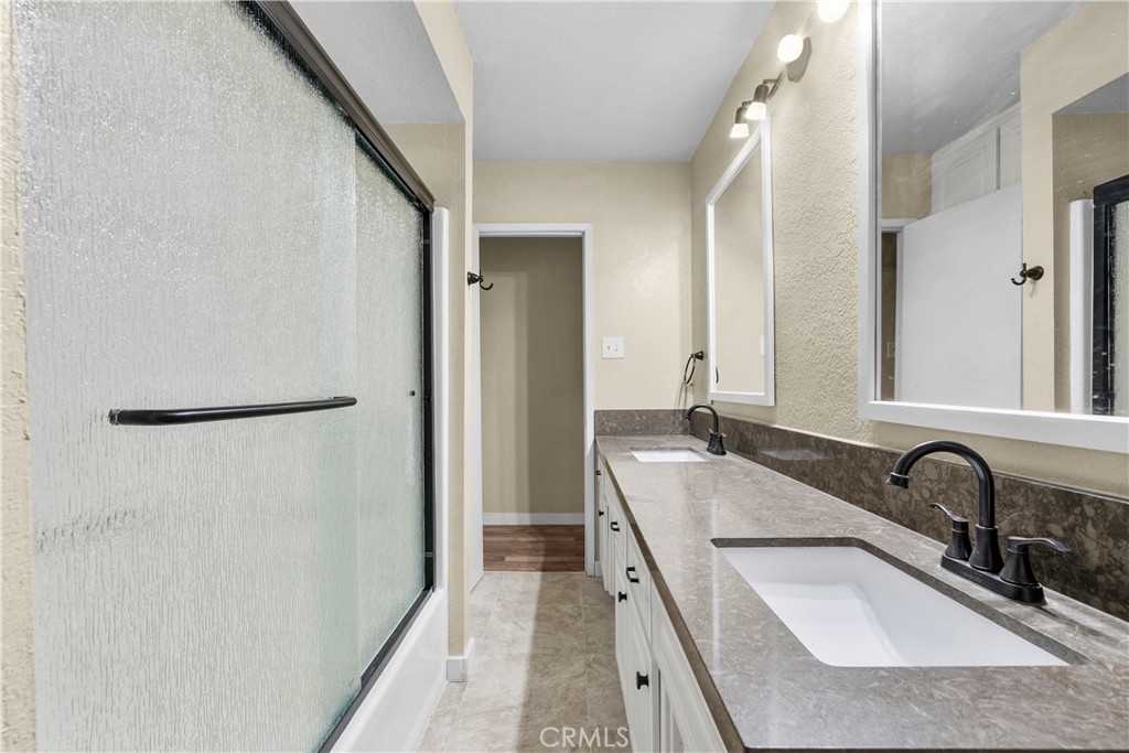 29570 Butterfield Way Tehachapi, CA 93561 - Photo 27 of 50 a bathroom with a granite countertop double vanity sink a mirror and a shower