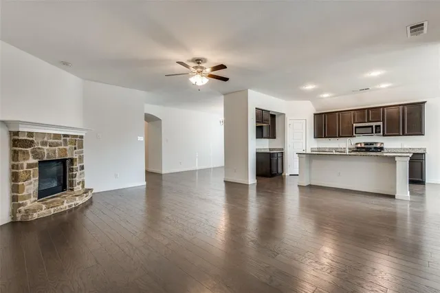 a view of a kitchen with furniture a ceiling fan and a fireplace