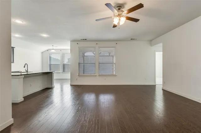 a view of an empty room with kitchen and a window
