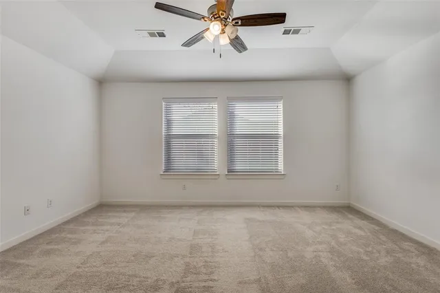 an empty room with chandelier fan and windows