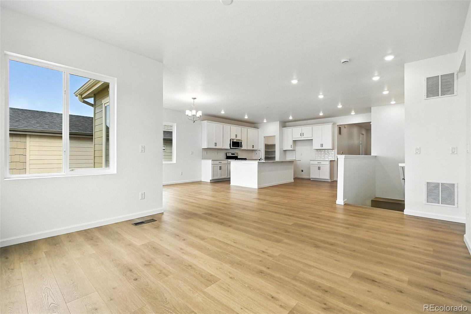 17075 West 92nd Loop Arvada, CO 80007 - Photo 10 of 33 a view of a kitchen with kitchen island a sink wooden floor and a large window