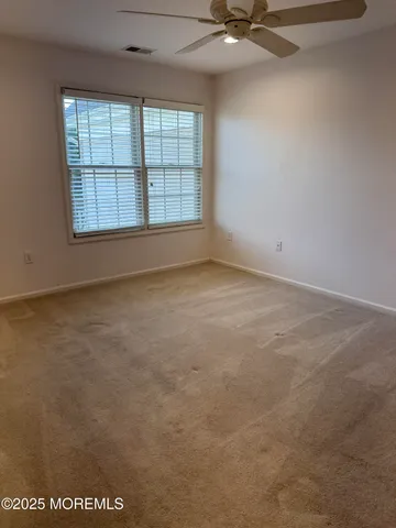 an empty room with windows and fan