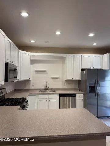 a kitchen with stainless steel appliances granite countertop a sink a stove a refrigerator a microwave and cabinets