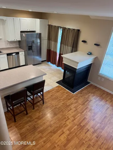 a living room with stainless steel appliances furniture a fireplace and a kitchen view
