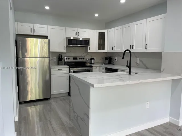 a kitchen with a sink a refrigerator a microwave and cabinets