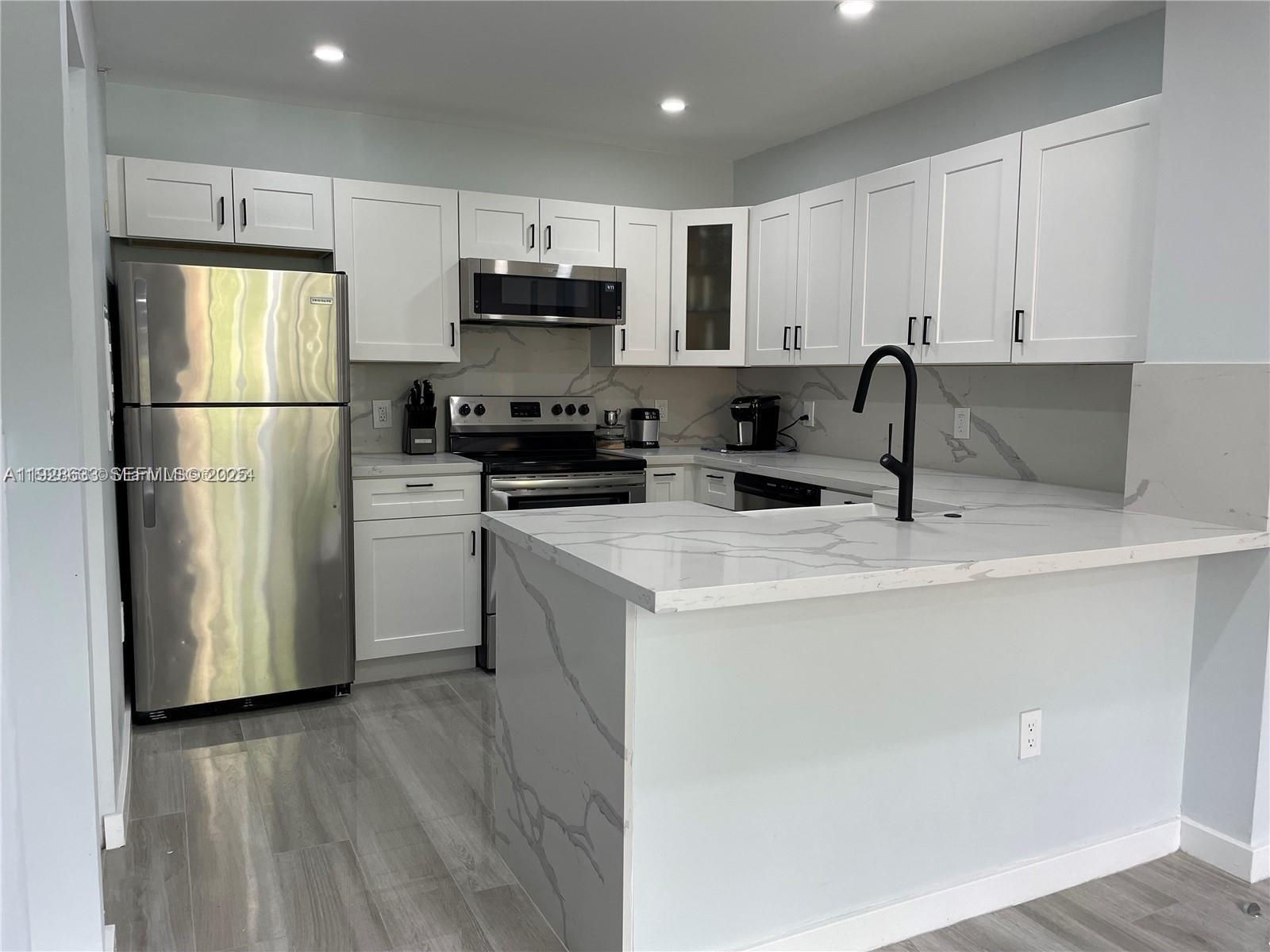 a kitchen with a sink a refrigerator a microwave and cabinets
